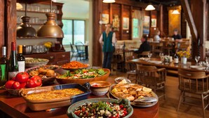 A buffet with various dishes, including a large casserole dish, salads, and a platter of grilled fish.