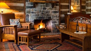 A cozy room with a stone fireplace, leather furniture, and a patterned rug.