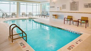 An indoor swimming pool with clear water, marked depth lines, and lounge chairs around the perimeter. - Springhill Suites by Marriott Carle Place Garden City (Carle Place)