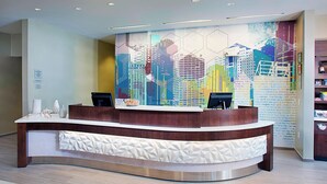 A reception desk with a cityscape mural, a white patterned counter, and a modern design. - Springhill Suites by Marriott Carle Place Garden City (Carle Place)