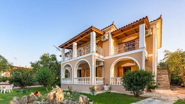 A two-story house with a balcony, a stone pathway, and a small garden. - Pansion Mary Studios (Zakynthos)