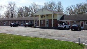 A motel with a central building and attached units, a parking lot, and a grassy area. - Colonial West Motel (Batavia)