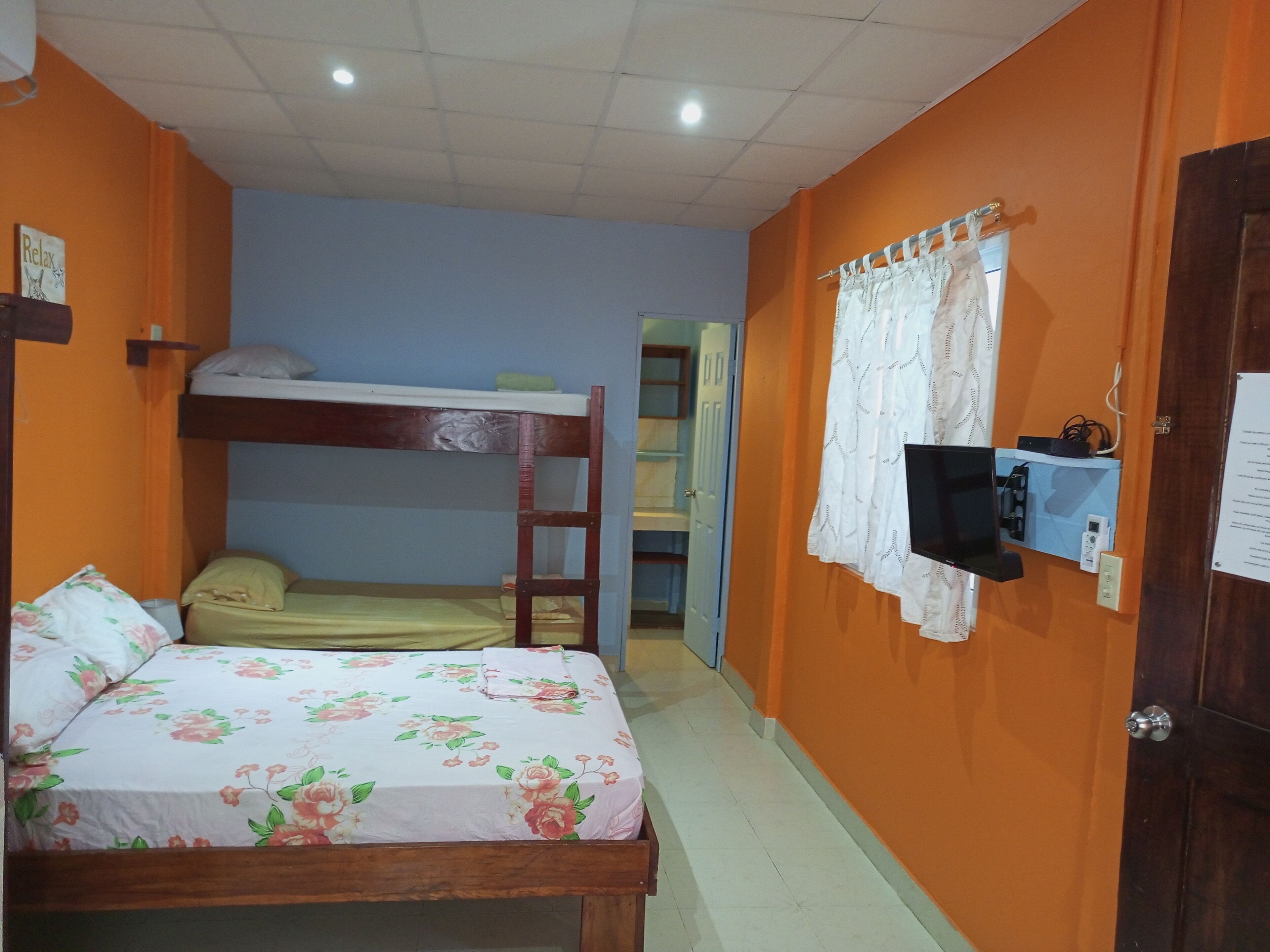 Una habitación con literas, un escritorio con computadora y una puerta con un cartel.