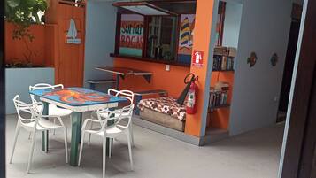 An outdoor seating area with a table and chairs, a small window with a sailboat decoration, and a fire extinguisher on the wall.
