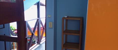 A room with a bunk bed, a wooden shelf, and a door leading to an outdoor area with a staircase.