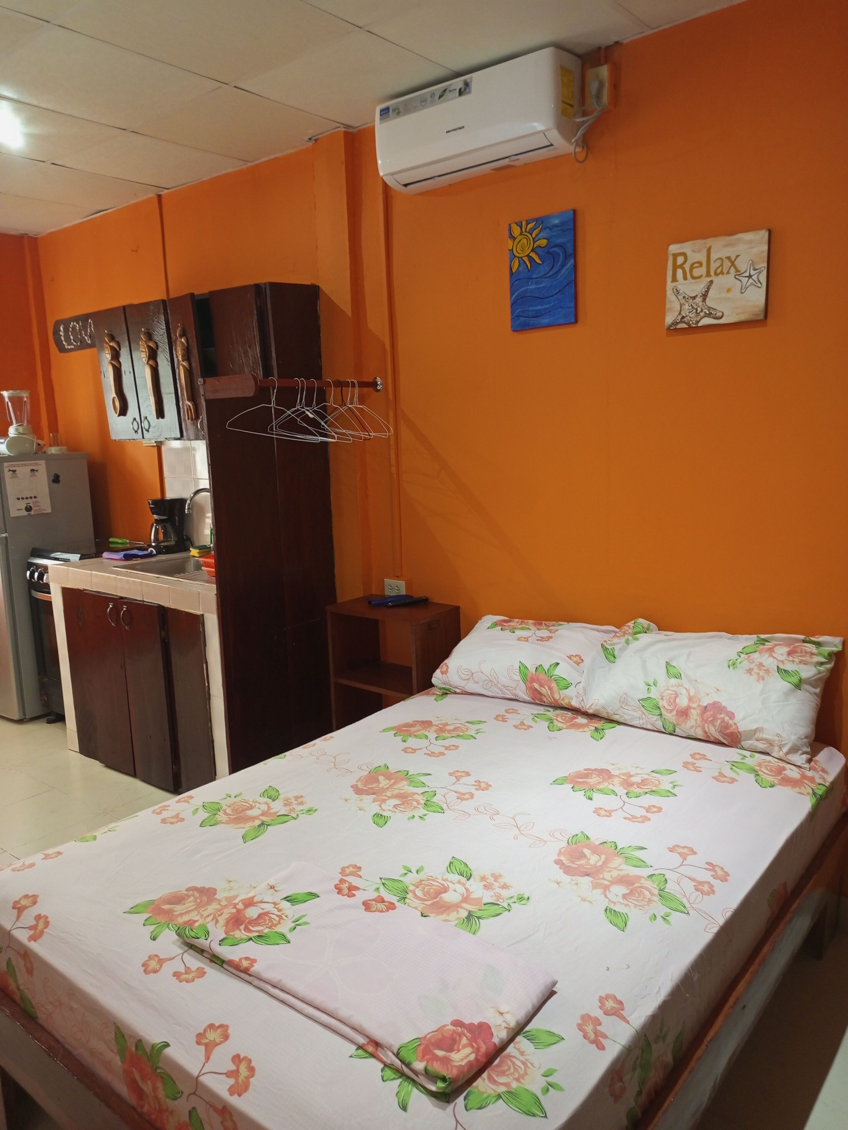 A room with a bed, a desk, a wardrobe, and an air conditioner.