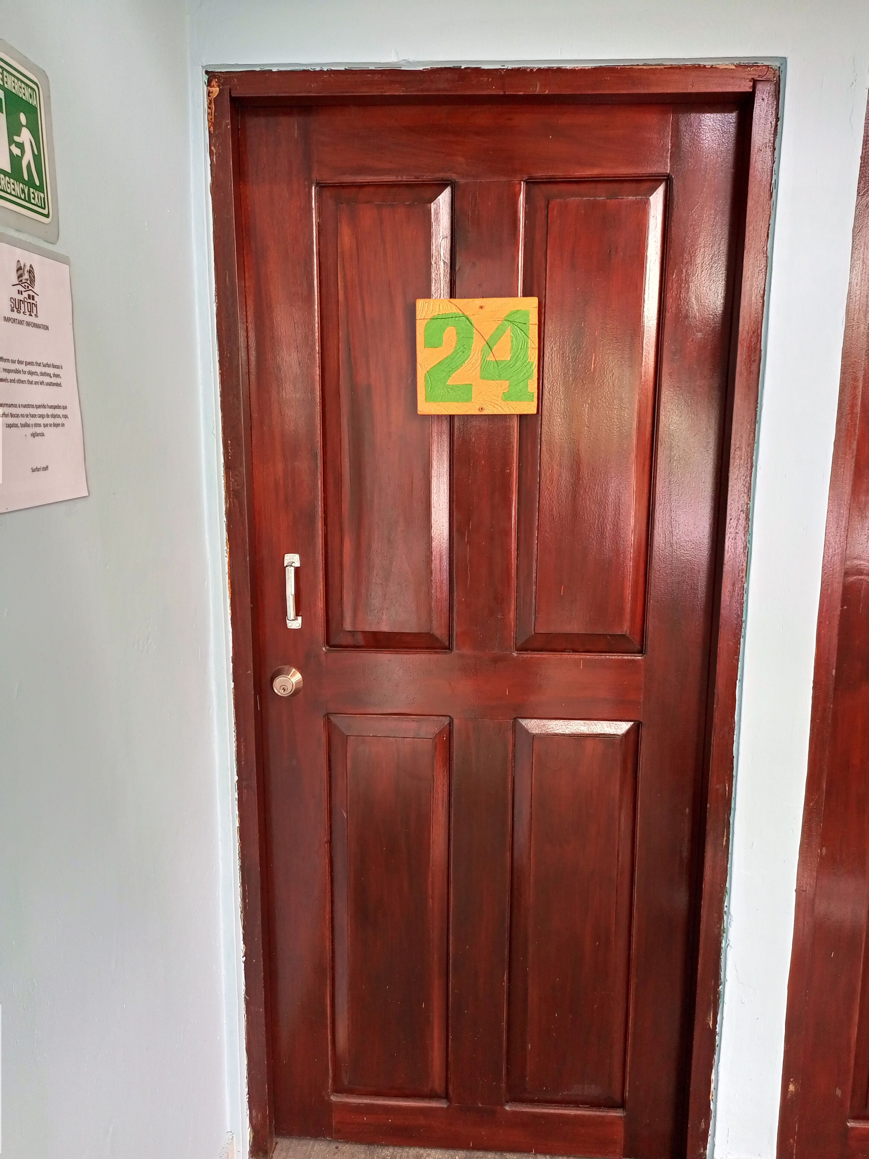 A wooden door with a green number 24 sign.