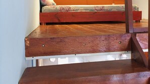 Un dormitorio con techo inclinado, una cama y una escalera de madera.
