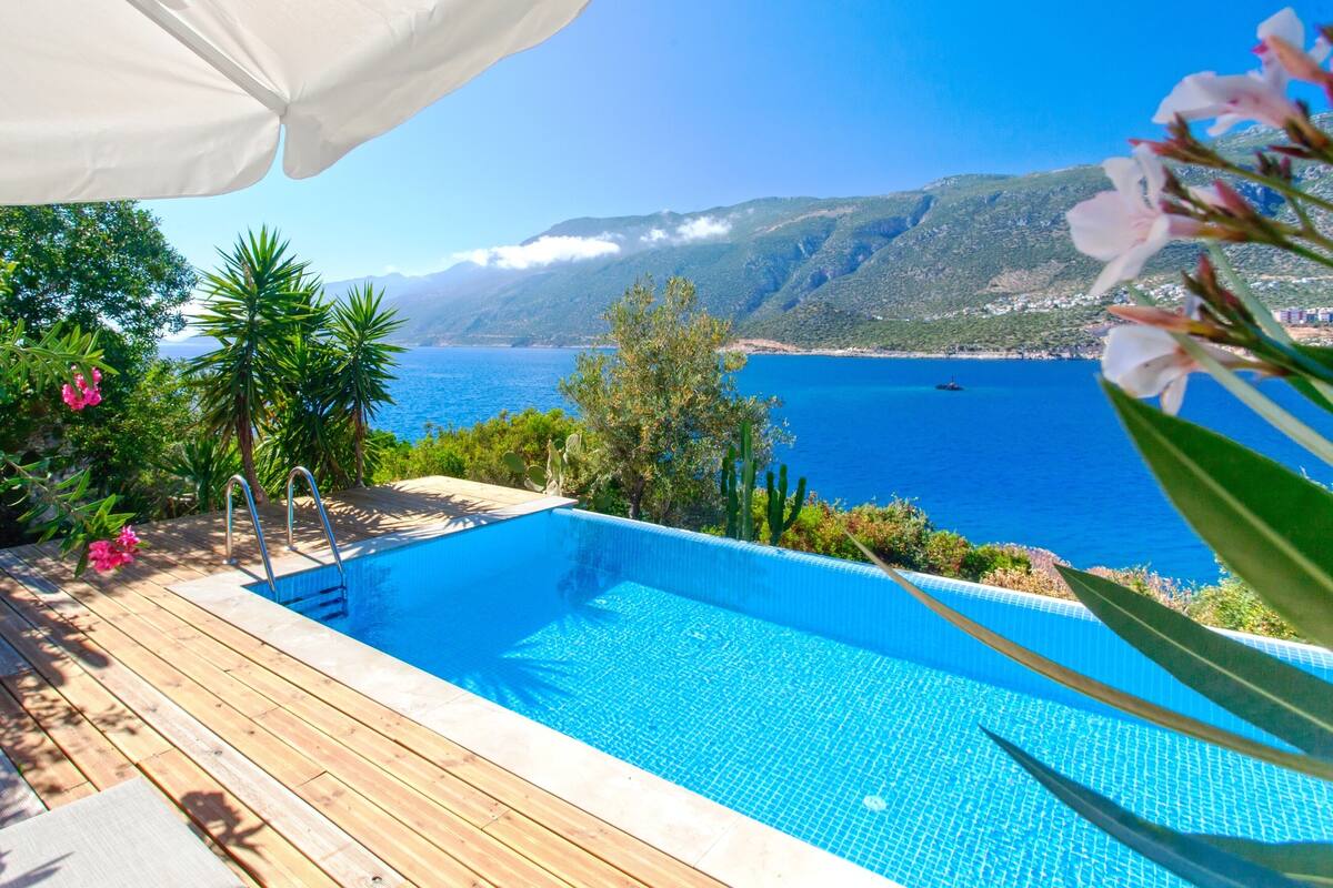 Un terrazzo in legno con piscina, immerso nel verde e con vista sul paesaggio costiero, tra montagne e mare.
