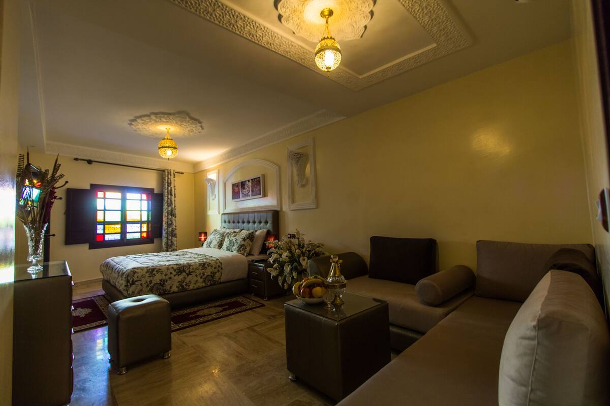 A bedroom with a bed, bedside table, lamp, and a window with curtains.