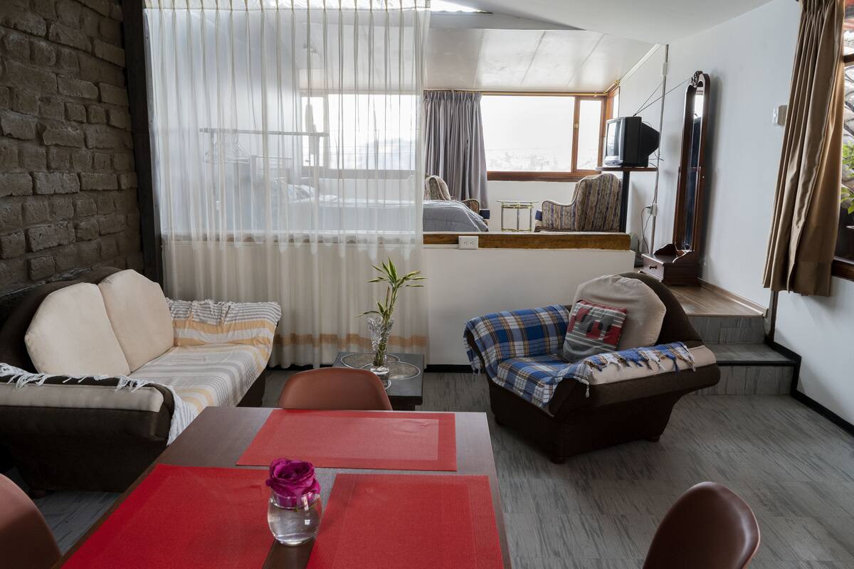 Ein Wohnzimmer mit Sofa, Sessel und Esstisch mit einer Vase.