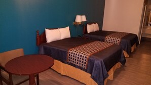 Une chambre d’hôtel avec deux lits, une petite table ronde et une lampe.