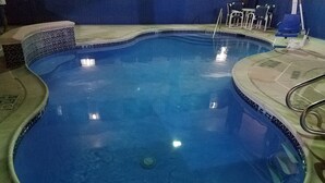 Une piscine dont le bord est revêtu de carreaux et qui est équipée d’une main courante sur un des côtés.