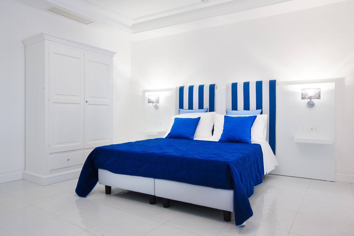 A bedroom with a bed, white wardrobe, and bedside lamps.