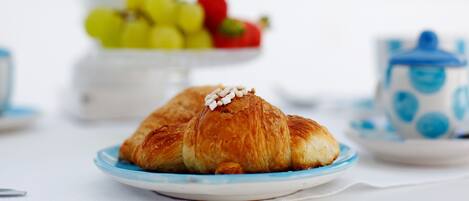 A plate with croissants and a bowl of fruit in the background.