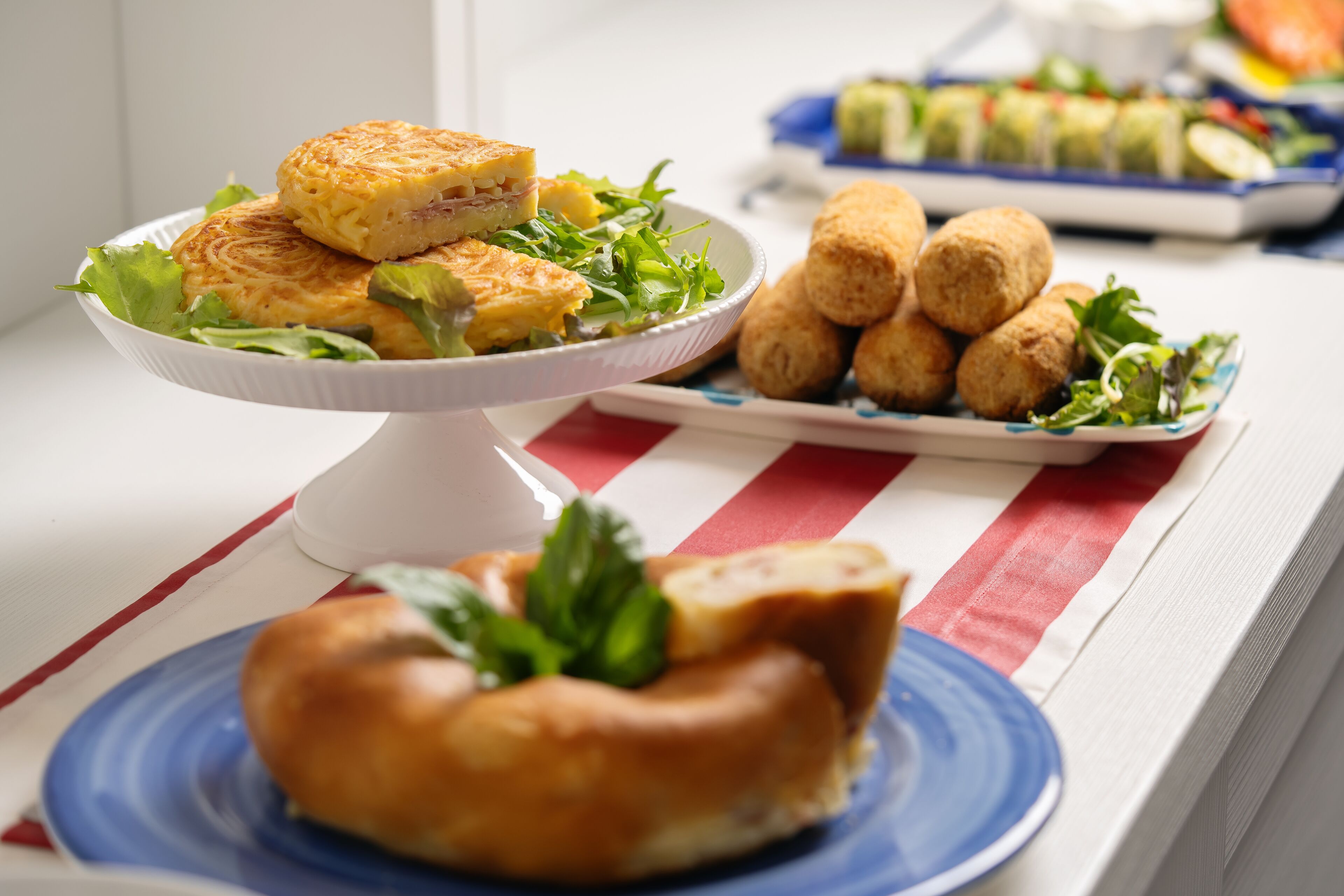 A table with a variety of food items including a pastry, a salad, and some bread rolls.