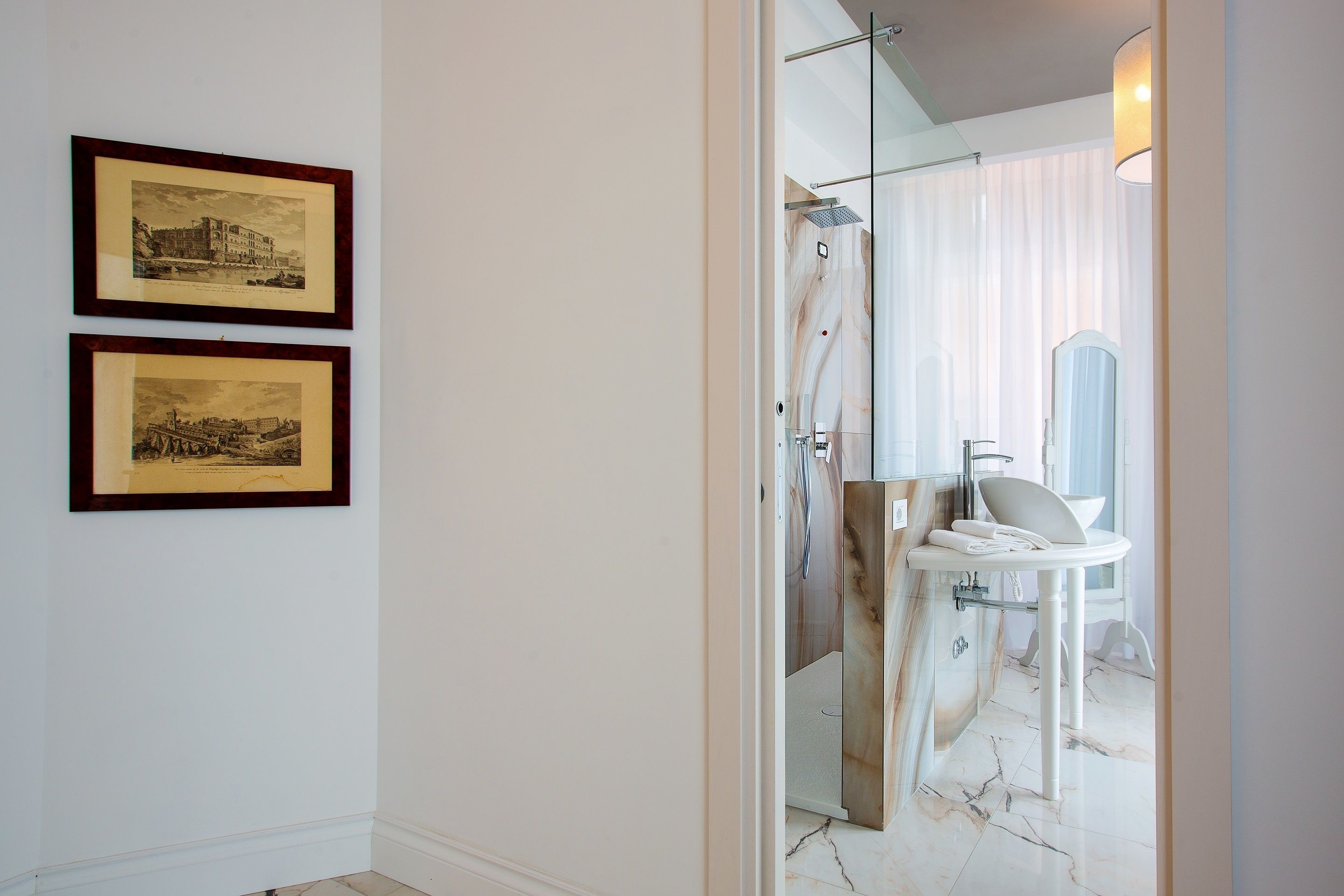 Une salle de bain avec une douche, un lavabo et deux tableaux encadrés au mur.