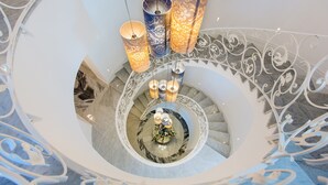 A grand spiral staircase with ornate railings and three hanging lamps with patterned shades. - Palazzo Murrano adults only (Vico Equense)