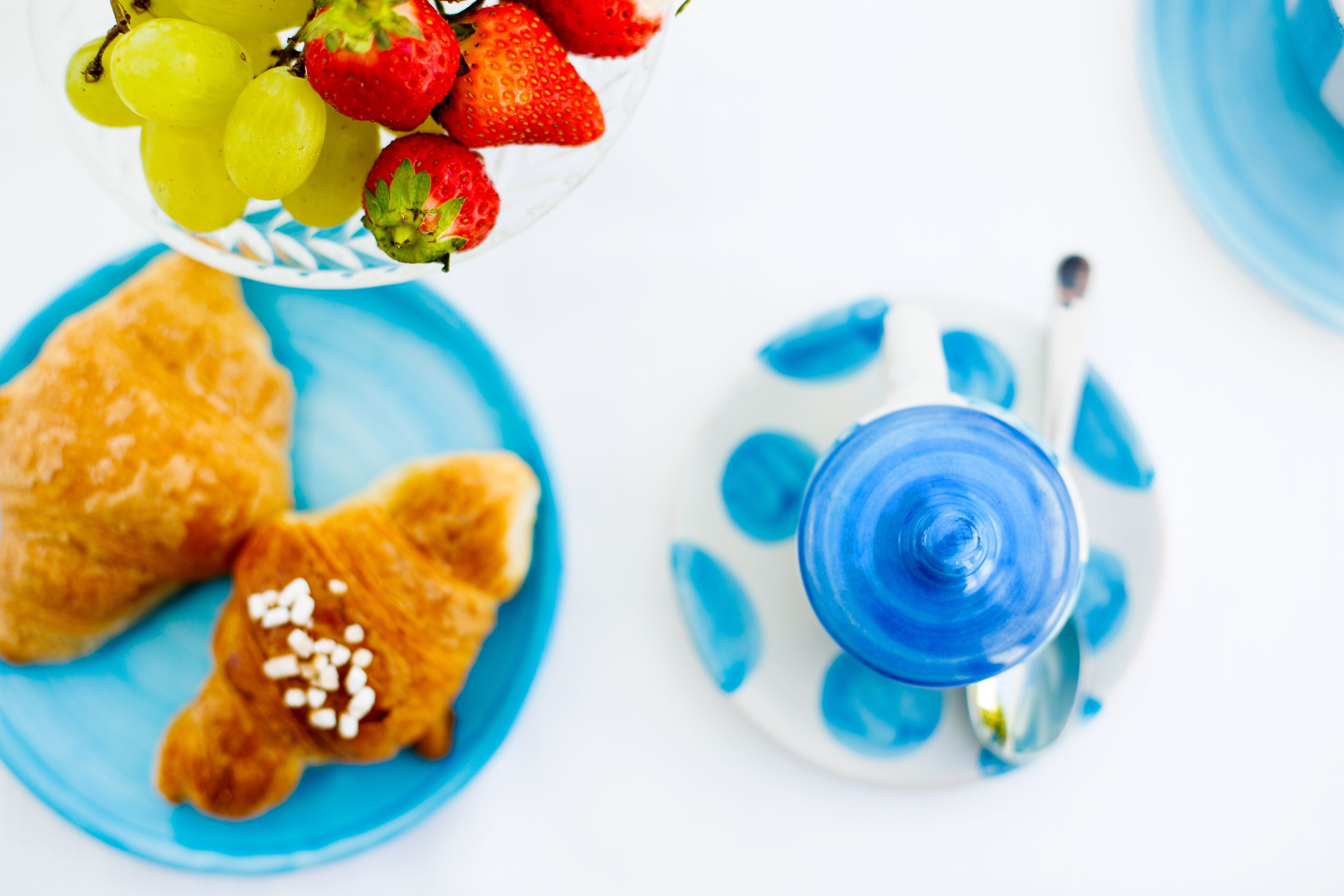 Une table sur laquelle se trouve une assiette bleue contenant des pâtisseries et un bol de fruits.