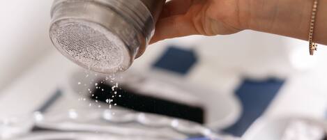 A hand sprinkling salt over cookies in a blue dish.