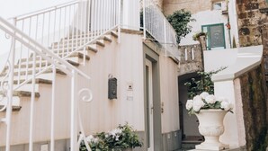 A narrow cobblestone street with a white staircase leading to a building with a stone archway. - Palazzo Murrano adults only (Vico Equense)