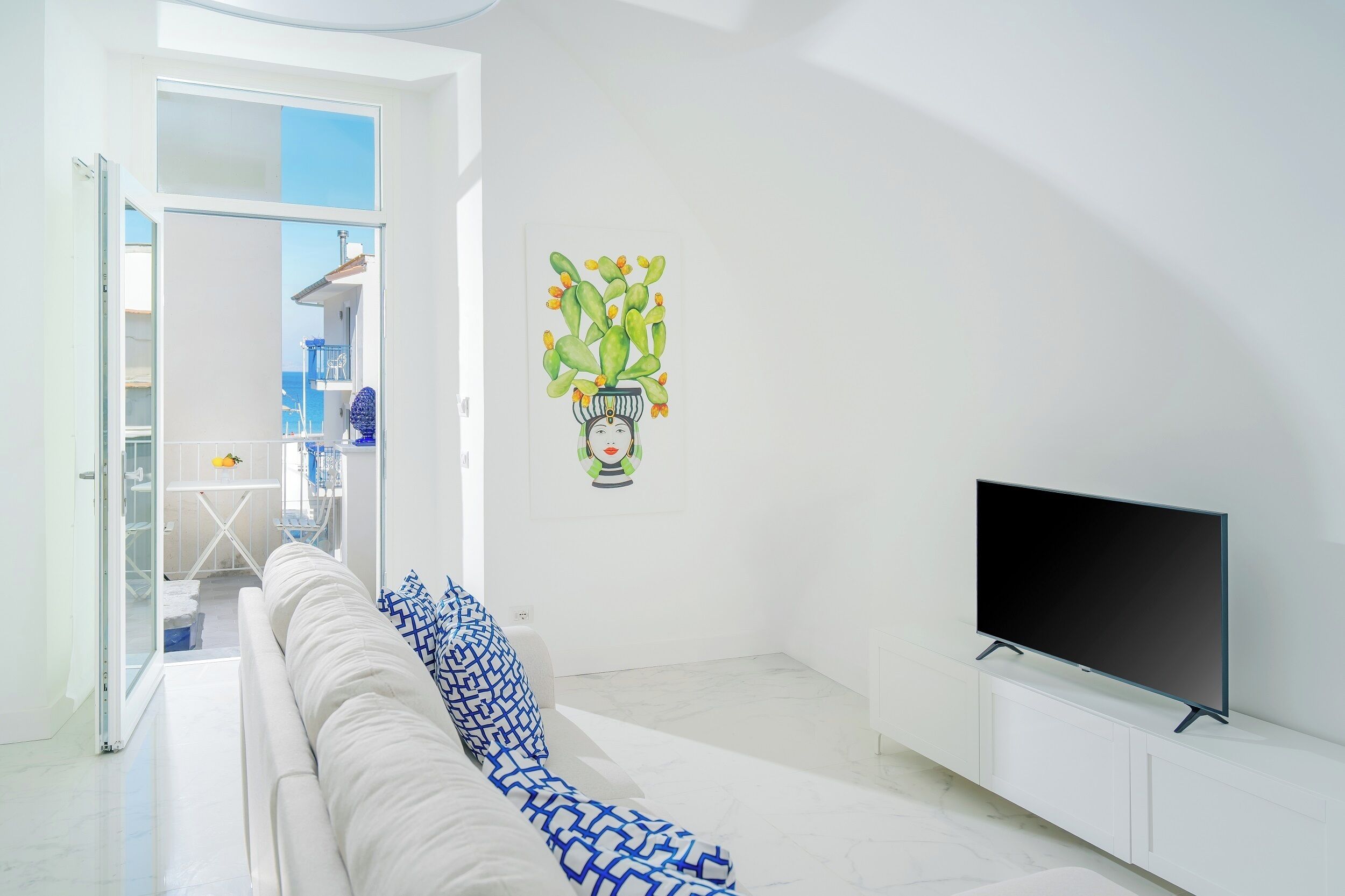 A modern living room with a sofa, a flat-screen TV, and a painting on the wall.