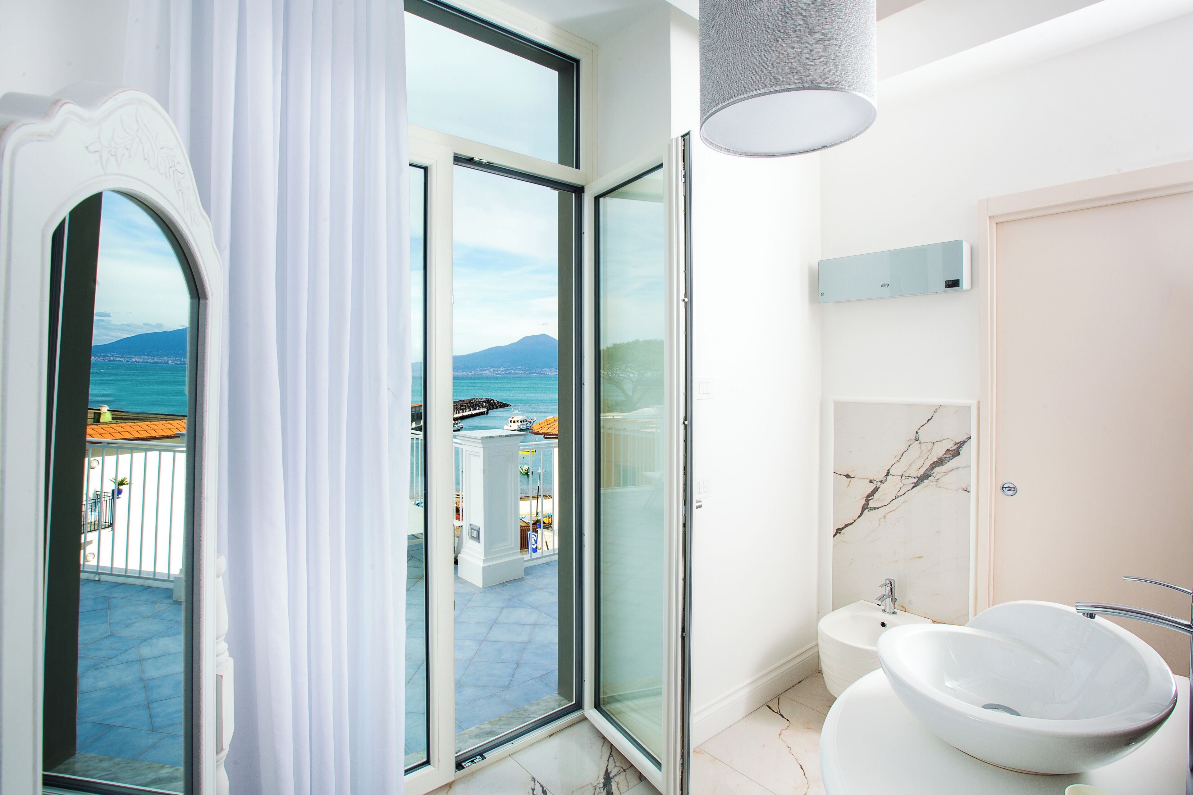 A modern bathroom with a large window, a white sink, and a shower.