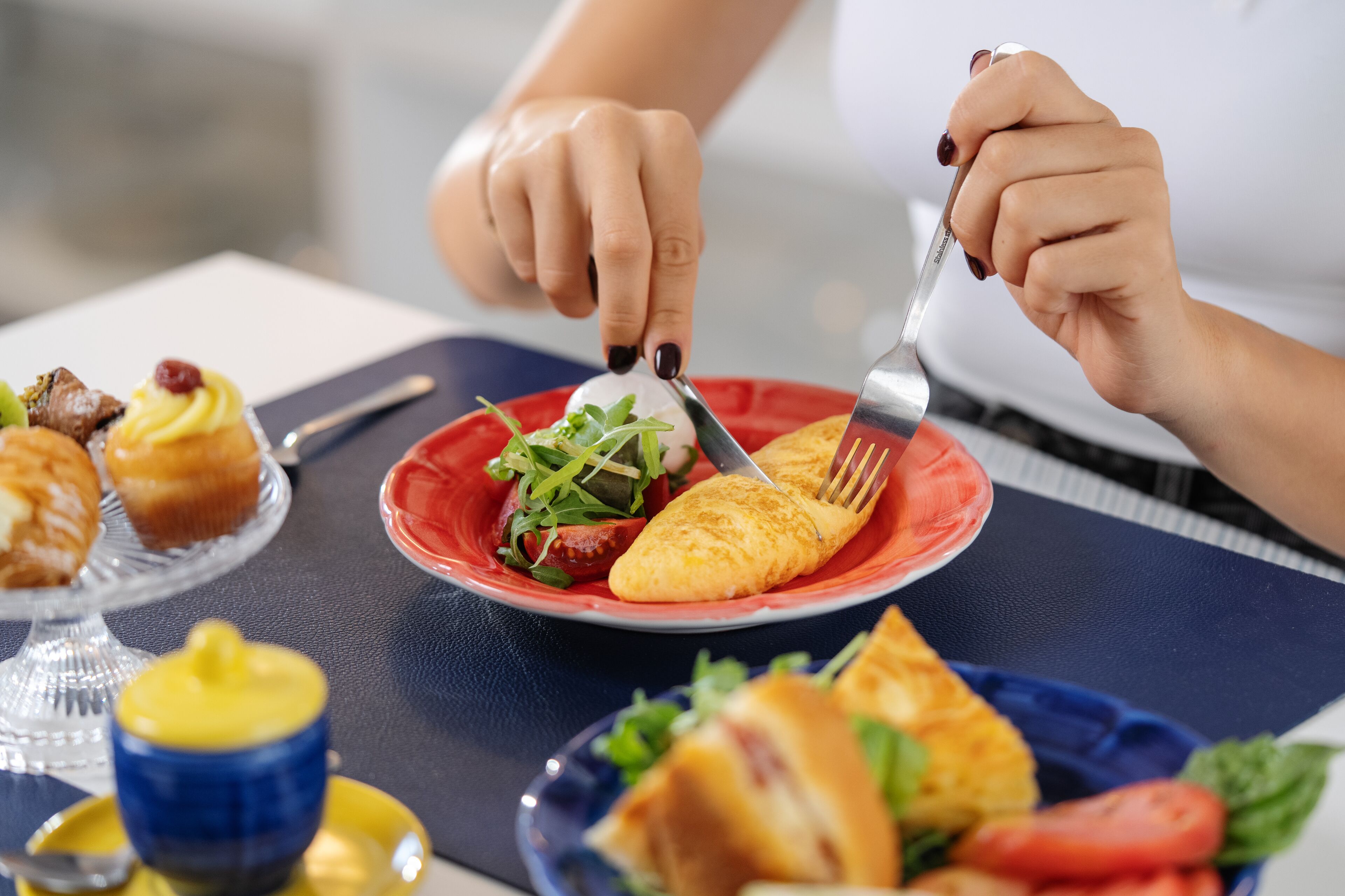 A dining table with a variety of food items including a plate with a salad, a muffin, and a sandwich.