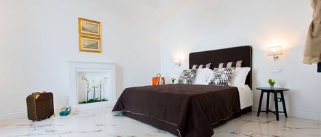 A bedroom with a large bed, a fireplace, and a suitcase on the floor.
