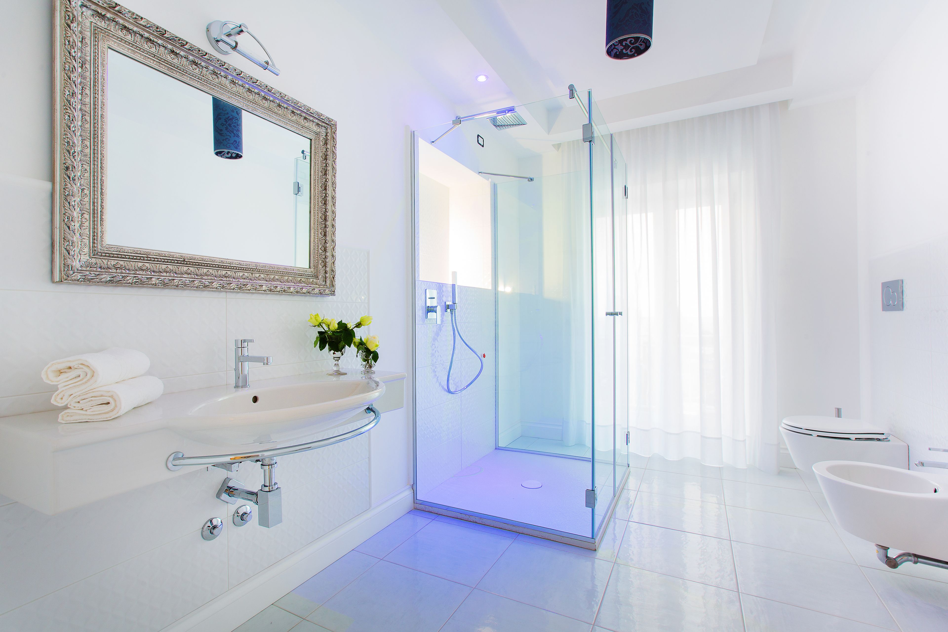 Un baño moderno con ducha envuelta en vidrio, bañera independiente y tocador con espejo y lavamanos.