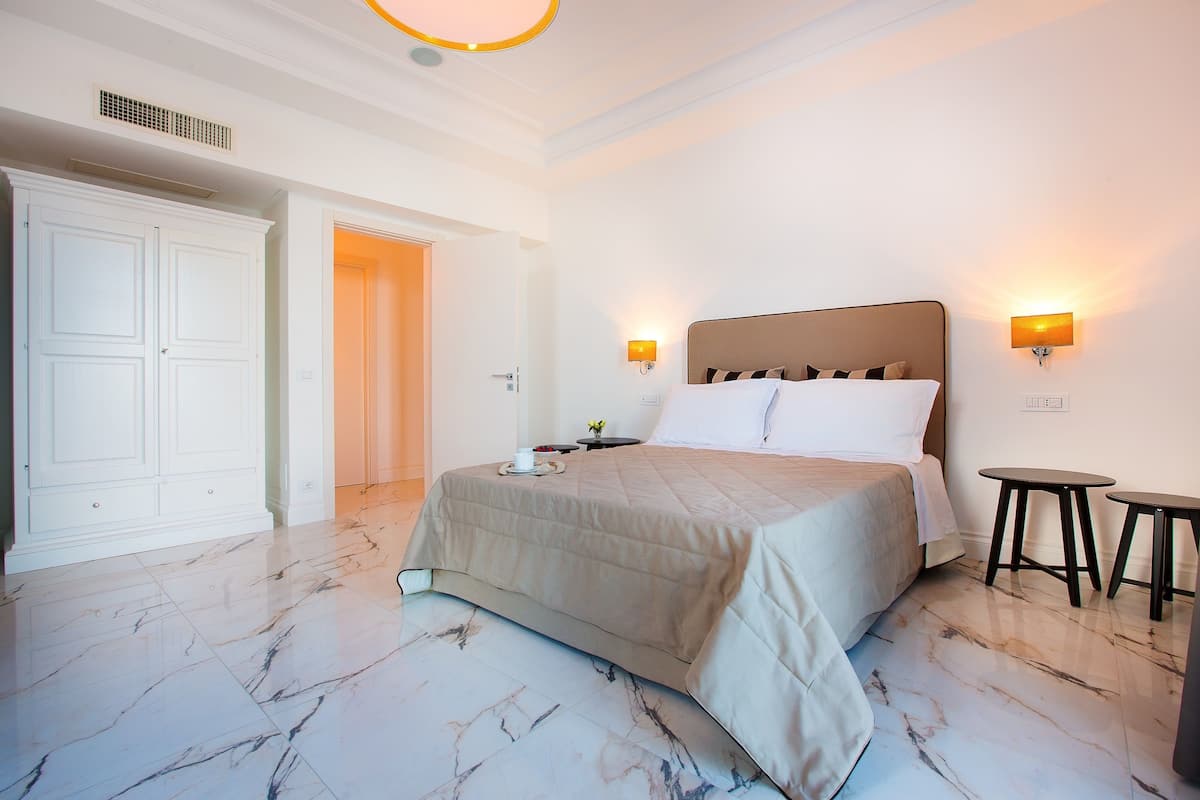 A hotel room with a large bed, two bedside tables, a wardrobe, and a bathroom door.