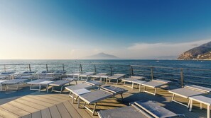 Aan een privéstrand, zwart zand, ligstoelen, strandlakens