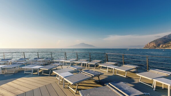 Privat strand, sort sand, solsenger og strandhåndklær
