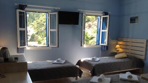 A room with two beds, a TV, and a table with a kettle. - Hotel Nostos (Ithaki)