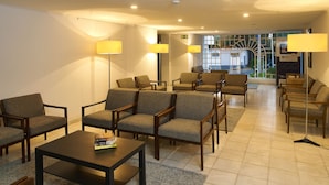 A hotel lobby with multiple seating areas, including sofas and chairs, arranged around a central table.