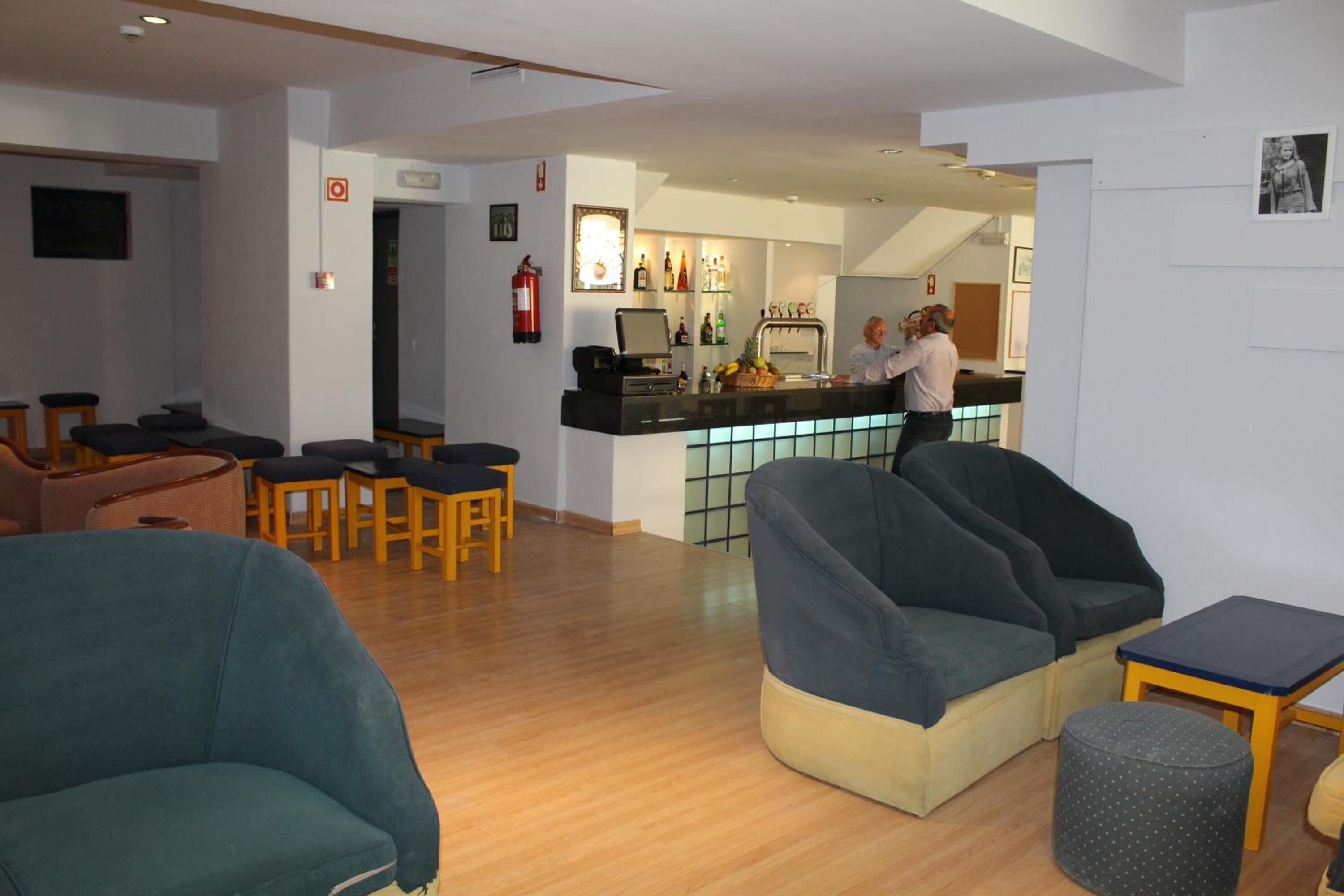 A hotel lobby with seating areas, a reception desk, and a bar.