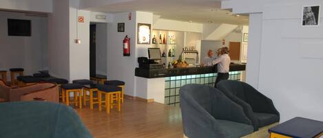 A hotel lobby with seating areas, a reception desk, and a bar.