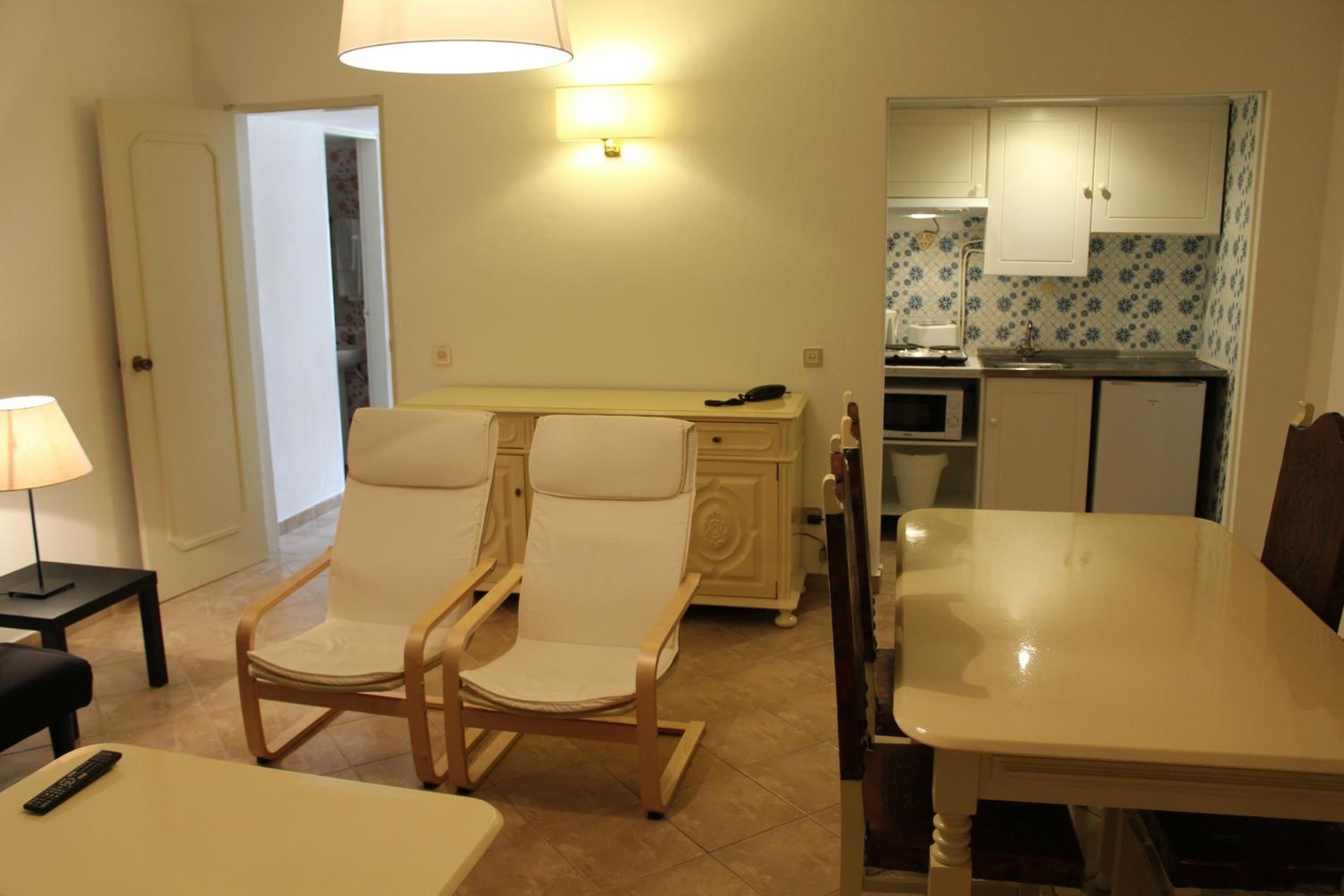 Una cucina compatta con microonde, forno e un piccolo lavandino. C'è un'area pranzo con un tavolo e due sedie.