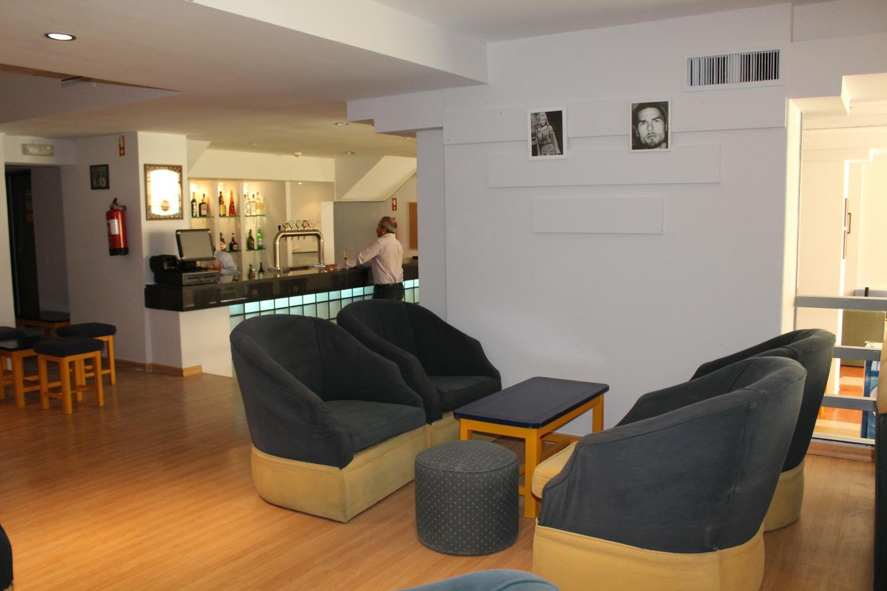 A hotel lobby with seating, a bar area, and a fire extinguisher.