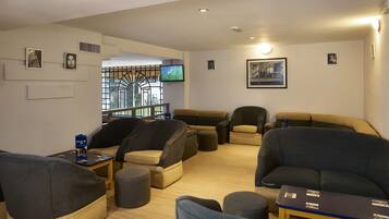 A modern living room with multiple seating options, a television, and artwork on the walls.