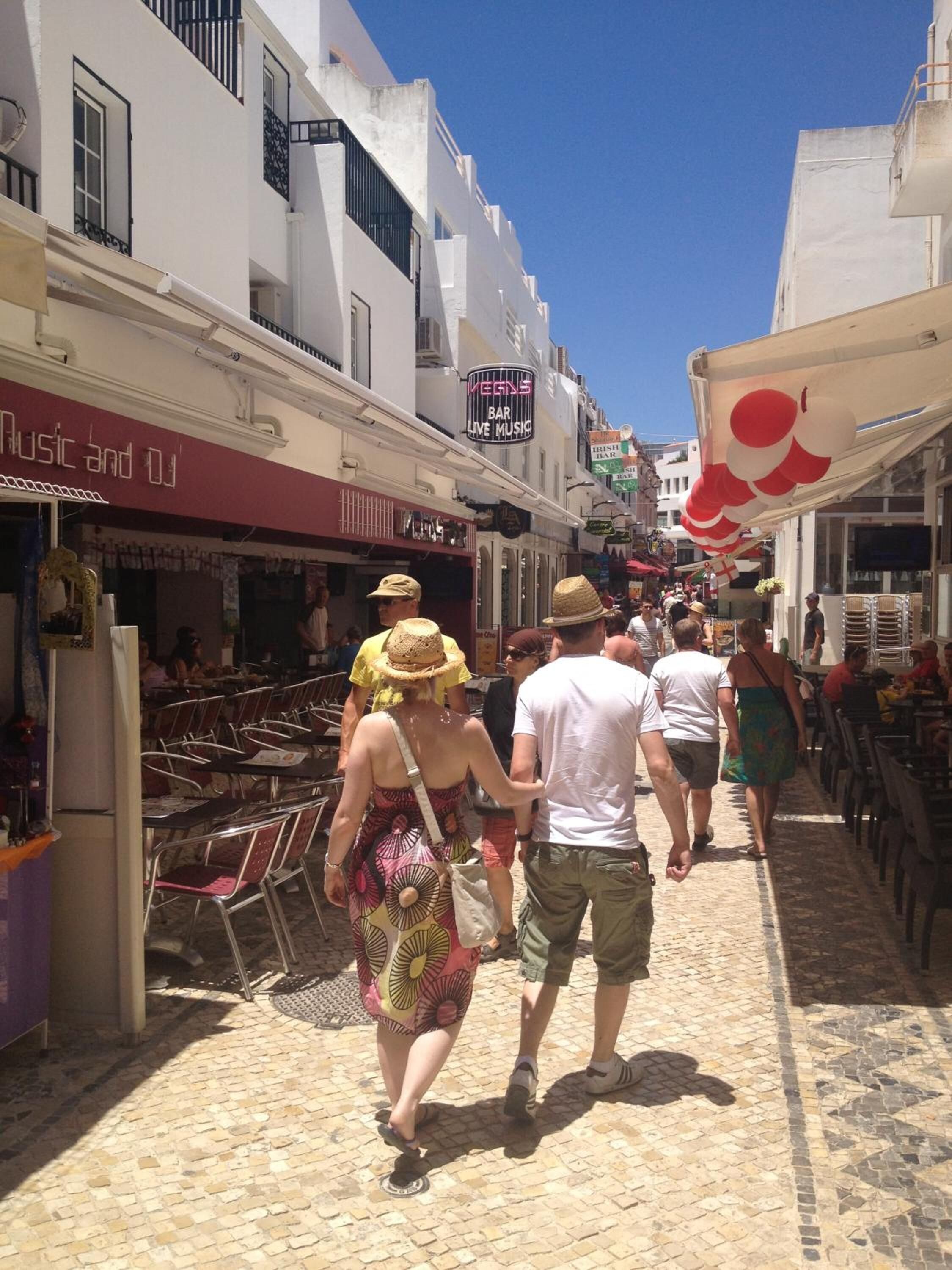 A narrow street lined with buildings, some with signs for bars and music venues.