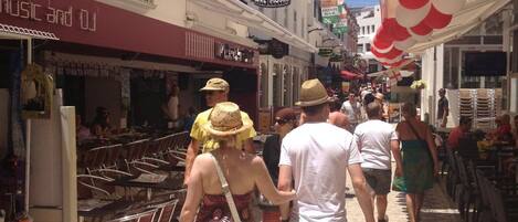 A narrow street lined with buildings, some with signs for bars and music venues.