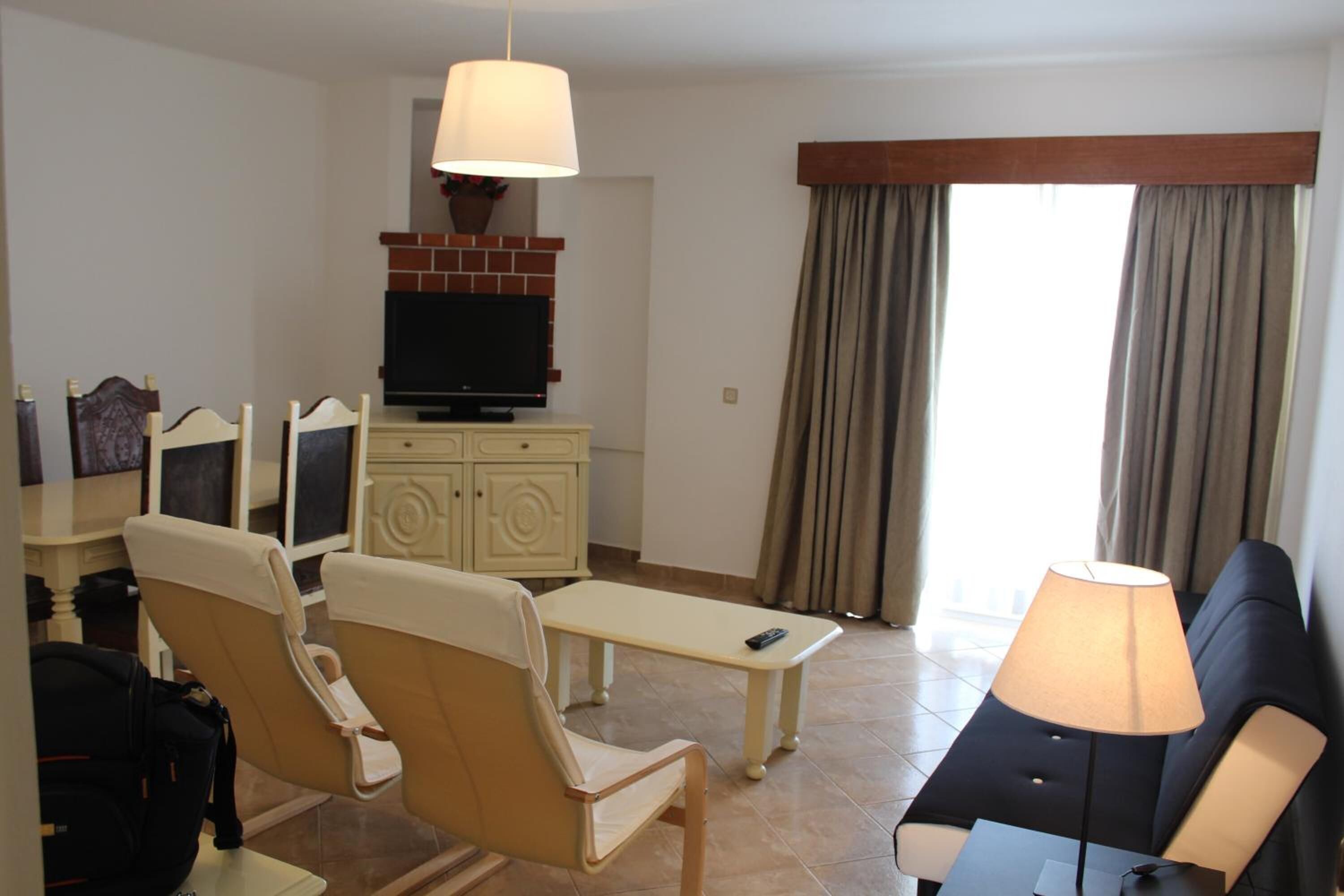 A living room with a television, a sofa, a table, and two chairs.