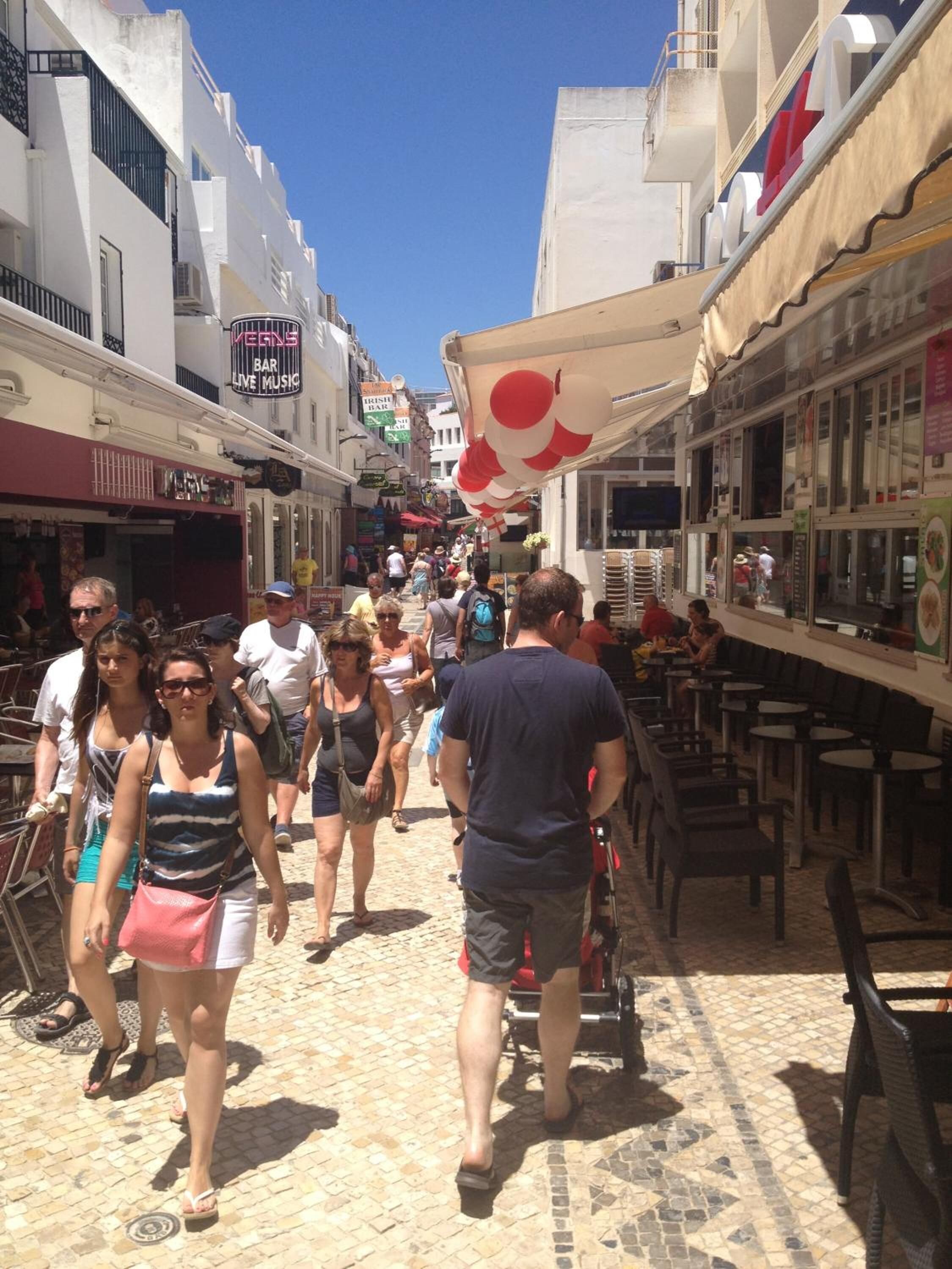 Une rue animée, bordée de boutiques et de terrasses.