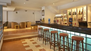 A bar area with stools, a counter, and a shelf with bottles.