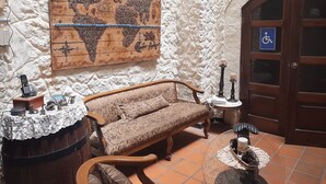 A room with a wooden sofa, a world map mural, a wooden door with a wheelchair sign, and a small table with candles. - Quito Antiguo (Quito)