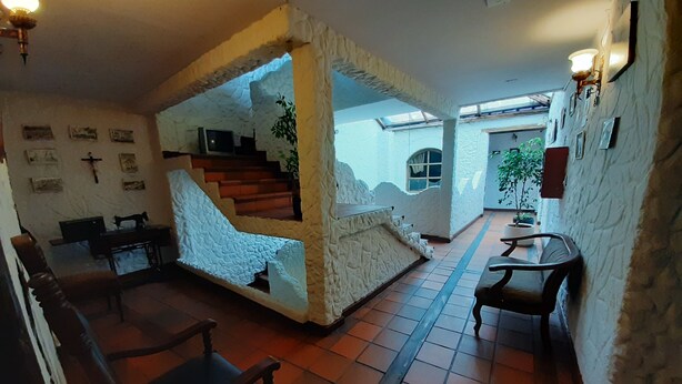 A room with a stone wall, wooden furniture, a staircase, and a view of the outside. - Quito Antiguo (Quito)