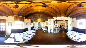 A restaurant with a high arched wooden ceiling, multiple tables with white tablecloths, and a central bar area. - Quito Antiguo (Quito)