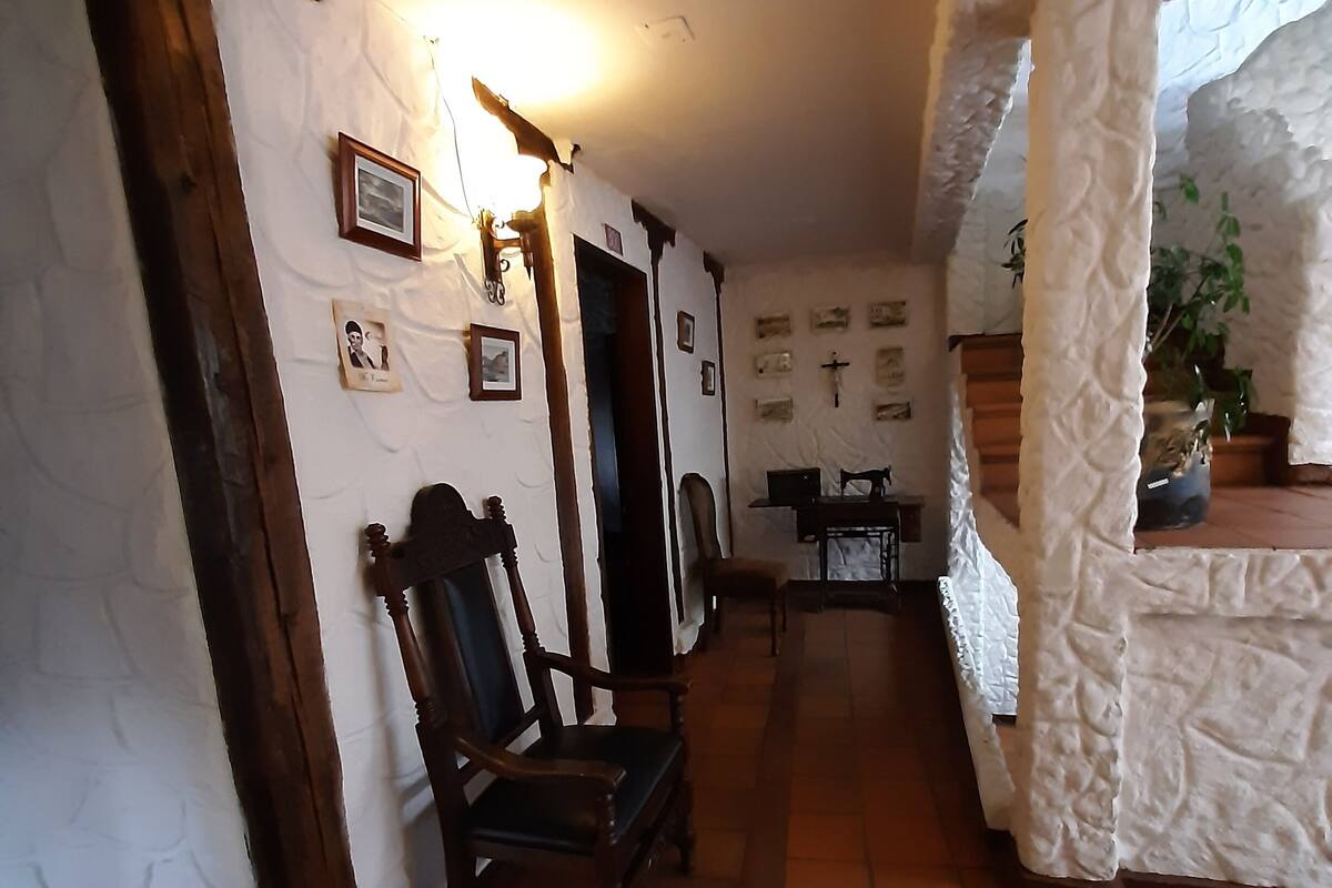 A hallway with rustic decor, including wooden chairs and a white textured wall.