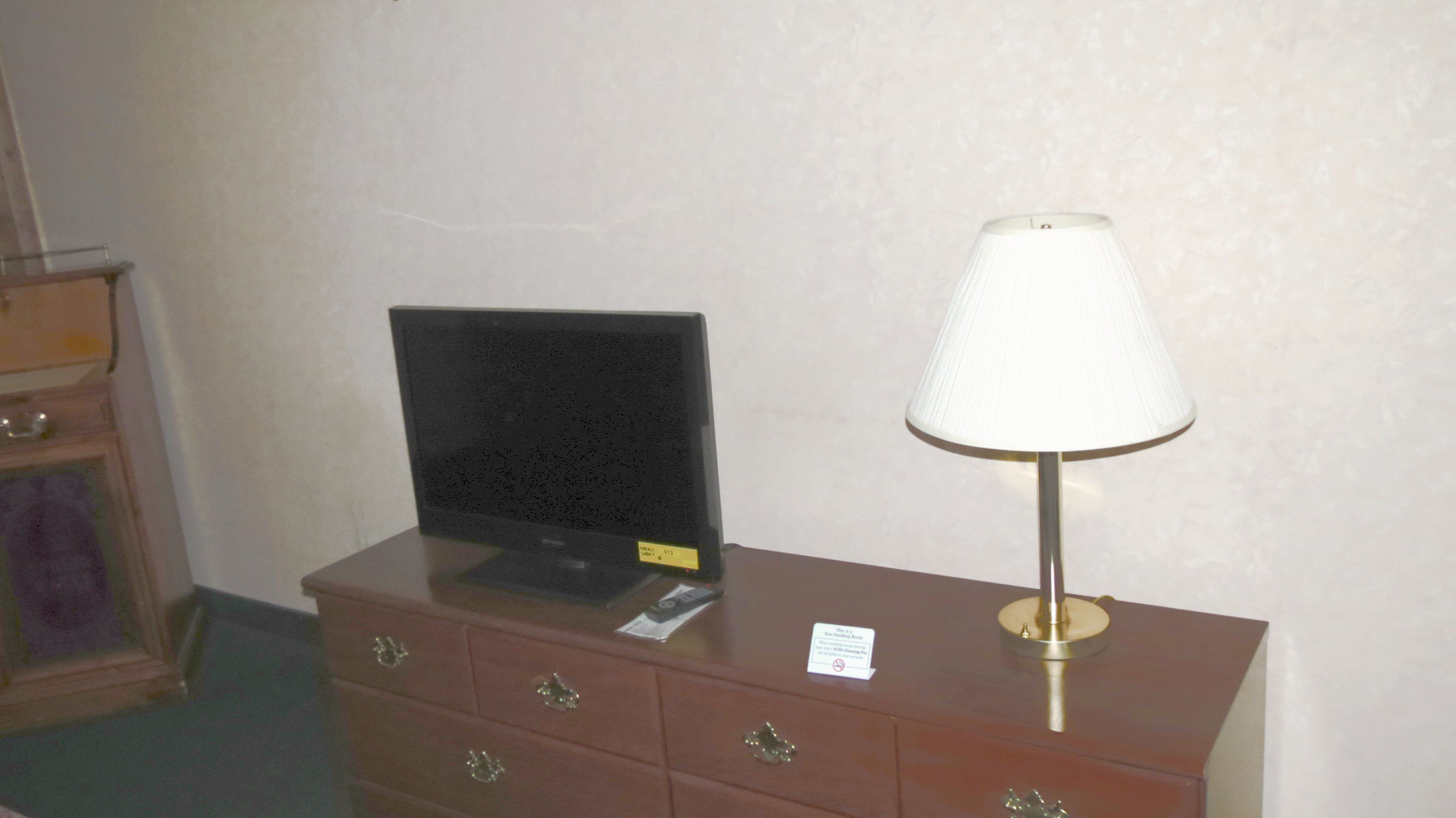 A wooden dresser with a television and a lamp.
